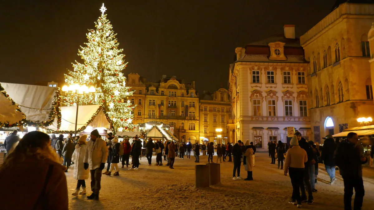 Plaza europea con un gran árbol iluminado y puestos abiertos durante Navidad