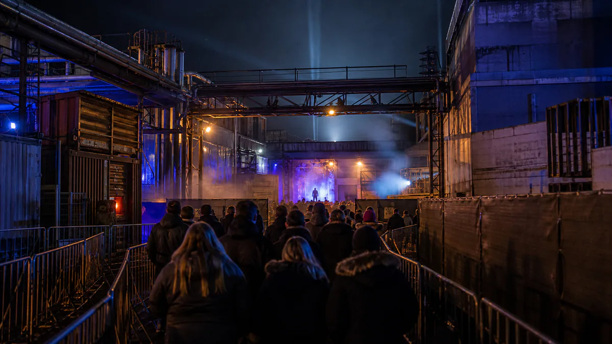 Recreación de un evento de terror industrial nocturno con naves, pasarelas y visitantes adultos